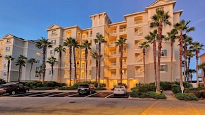 A multi-story hotel with a symmetrical facade, balconies, and palm trees. - Coastal Breeze Luxurious Coastal Villa Steps to Cinnamon Beach Beautiful Pools! Perfect for Families (Palm Coast)