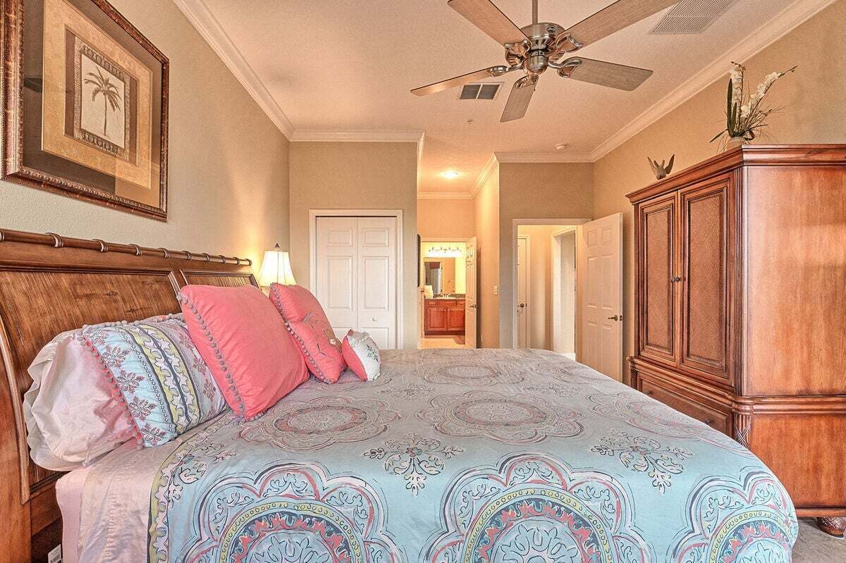 A bedroom with a bed, a ceiling fan, a wooden cabinet, and a framed picture on the wall.