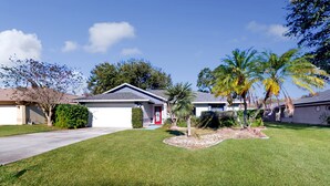 A residential area with houses, a well-maintained lawn, and palm trees. - Coastal Home Near Beach With Private Outdoor Pool, Washer/dryer, AC, & Wifi (Palm Coast)