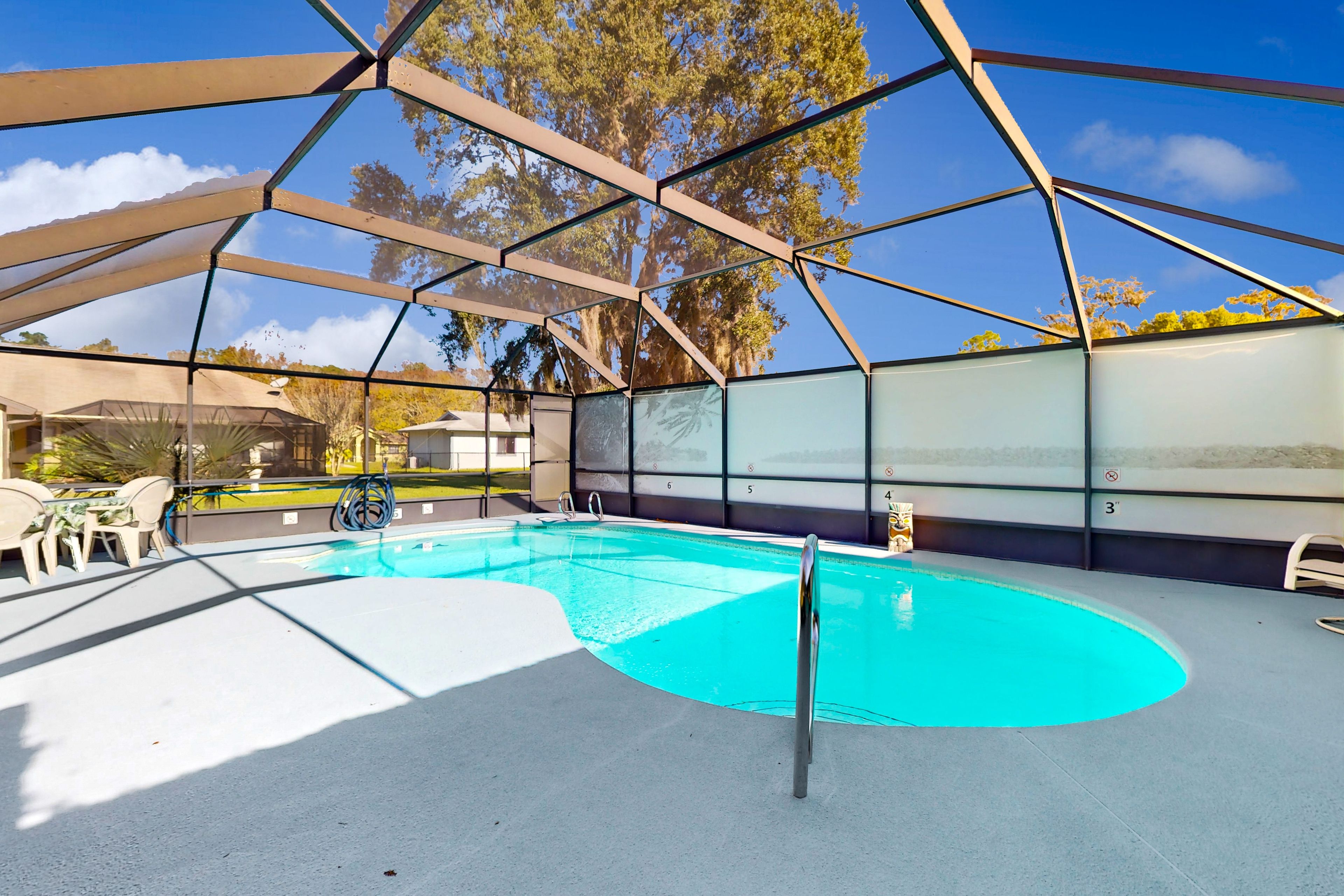 A covered outdoor swimming pool with a clear blue water feature, surrounded by a metal frame structure.