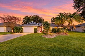 A residential property with a well-maintained lawn, a garage, and a house with a red door. - Coastal Home Near Beach With Private Outdoor Pool, Washer/dryer, AC, & Wifi (Palm Coast)