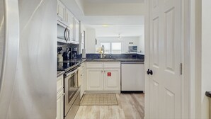 A modern kitchen with white cabinetry, stainless steel appliances, and a granite countertop. - Beautiful Amelia Island Townhome With Pool & Tennis, Central AC (Fernandina Beach)