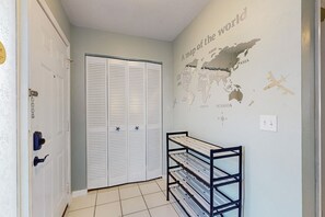 A hallway with a white door, a closet with louvered doors, and a wall-mounted shelf with a world map. - Centrally Located Dog-friendly Home With Beach Gear & Patio - Snowbird-friendly (Palm Coast)