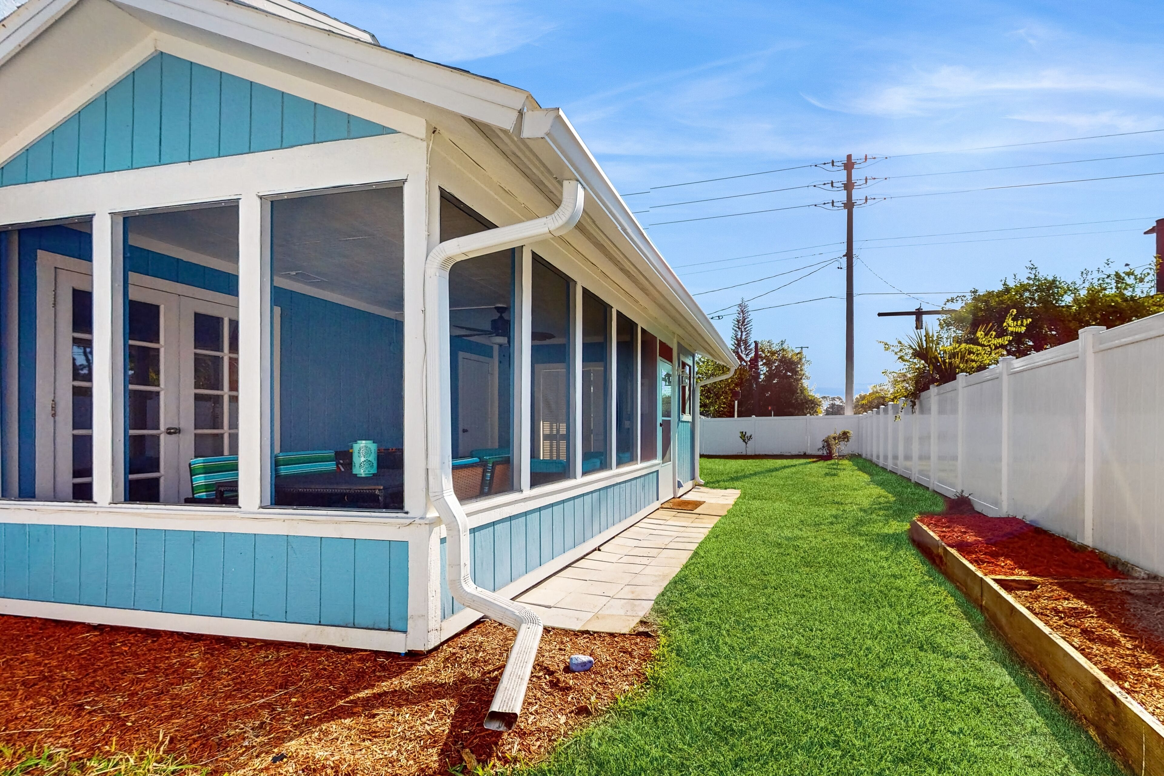 A house with a covered porch, a well-maintained lawn, and a wooden deck.