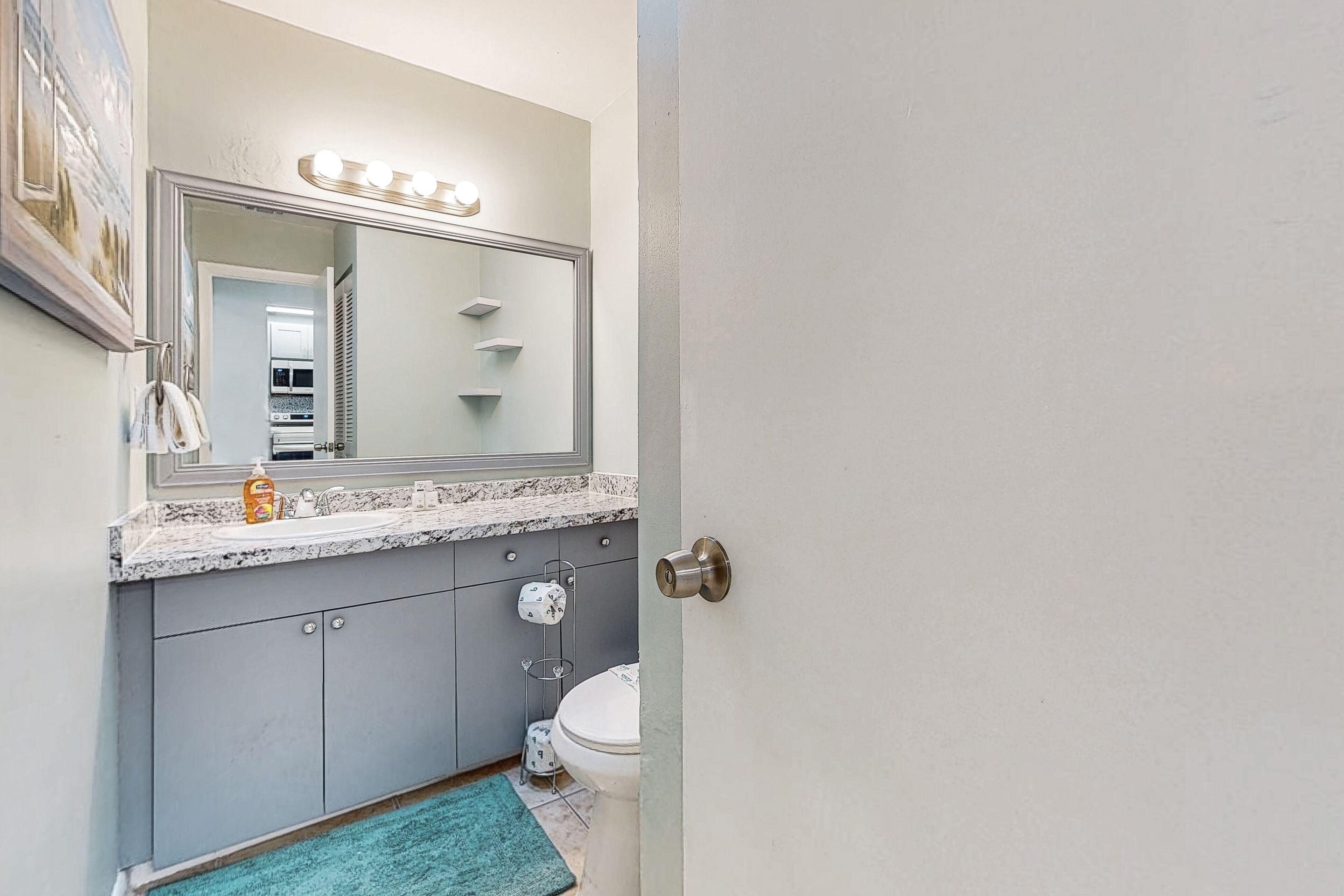 Une salle de bain équipée d’un meuble-lavabo, d’un lavabo, d’un miroir et de toilettes.