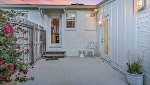 A residential property with a white exterior, a wooden fence, a white bench, a potted plant, and a small porch area. - Bright 1940s Beach Cottage With Cabana Plus Private Pool (St. Augustine)