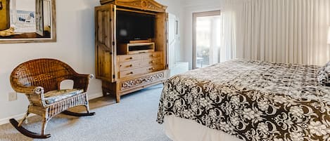 A bedroom with a bed, a rocking chair, a wooden cabinet, and a ceiling fan.