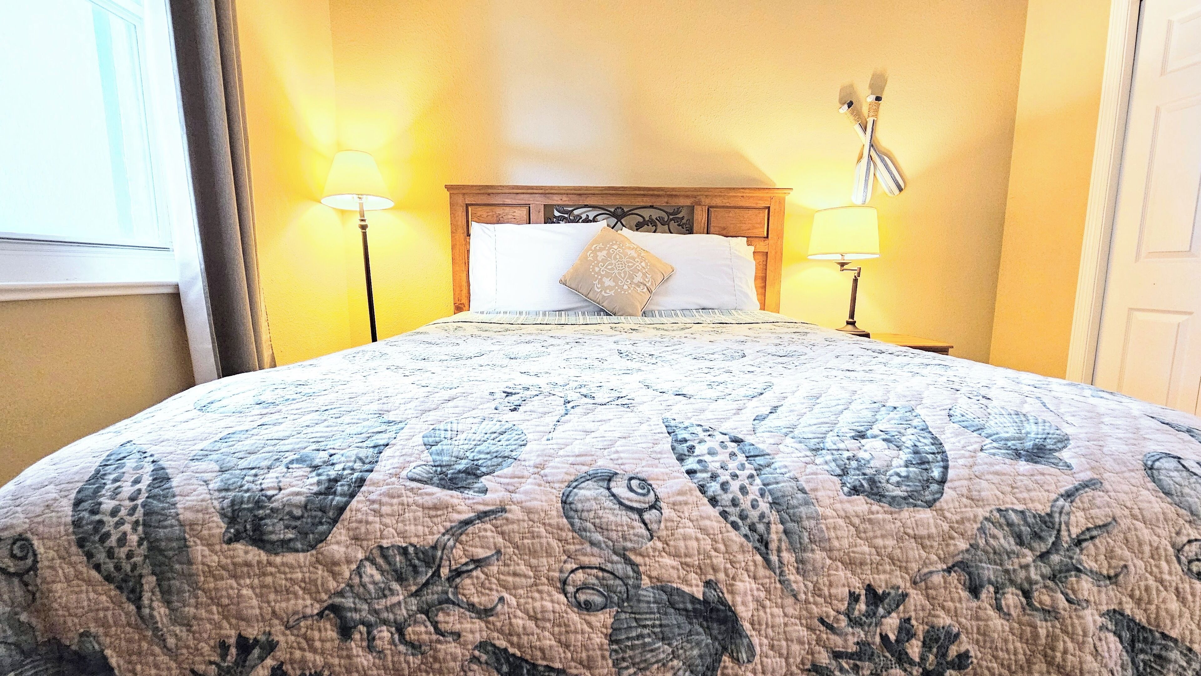 A bed with a floral quilt, two bedside lamps, and a wooden headboard.