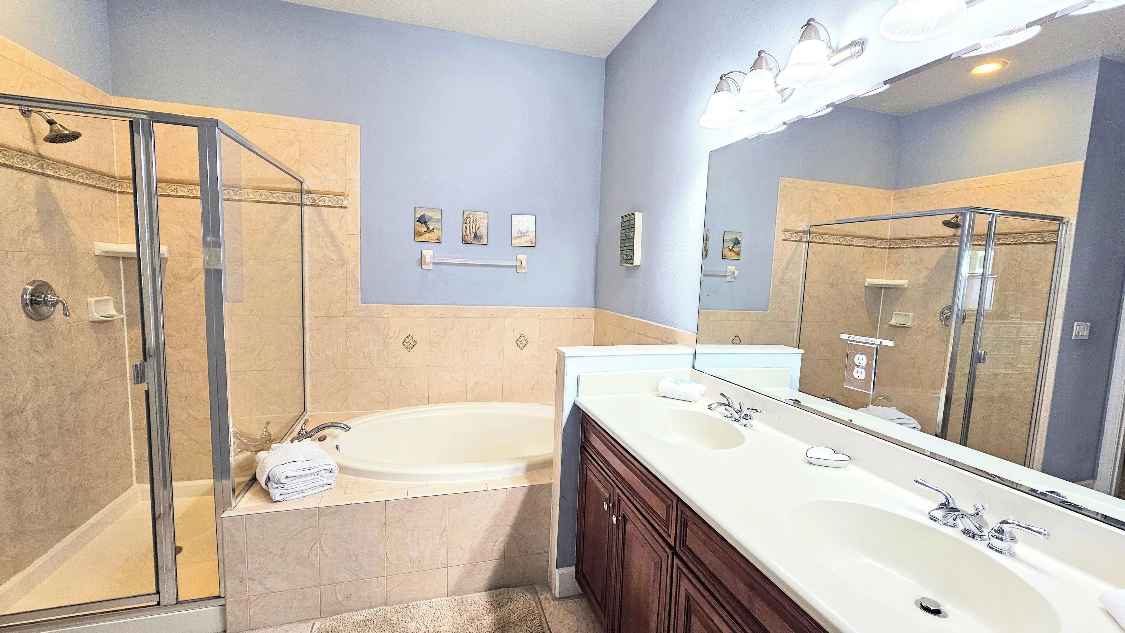 A bathroom with a walk-in shower, a bathtub, and a double vanity with a large mirror.