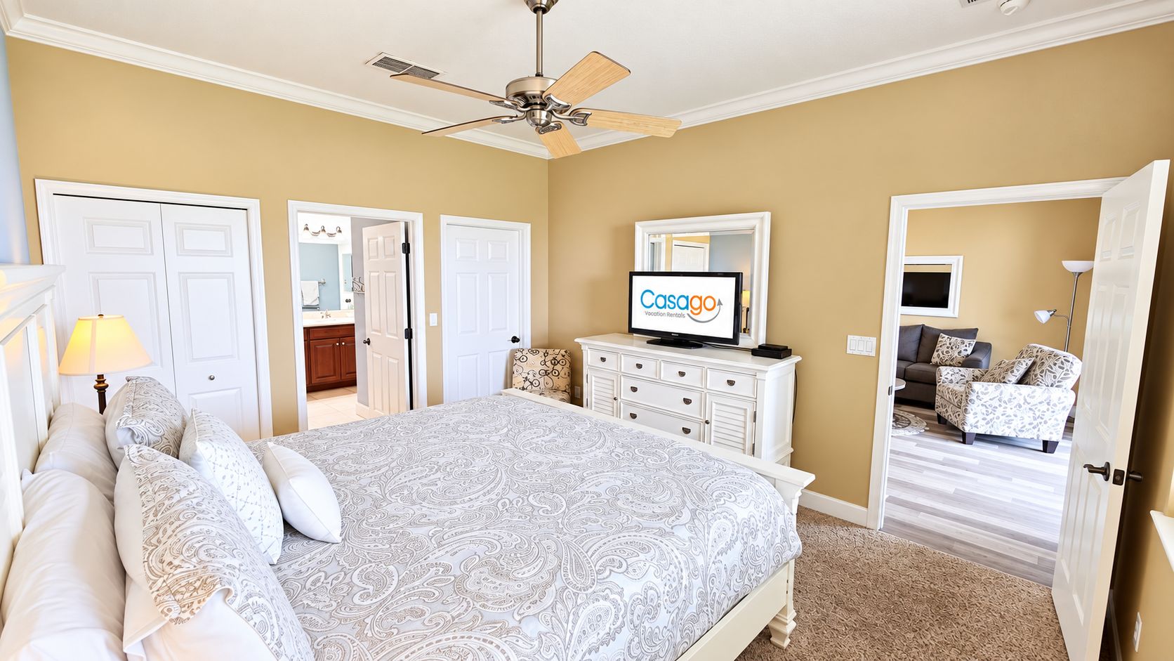 Une chambre à coucher comprenant un lit, une commode, un téléviseur et une porte donnant sur une autre pièce.