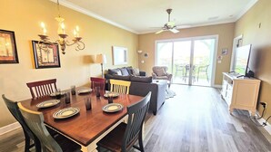Un coin repas avec une table en bois dressée pour quatre personnes, un lustre et un canapé en arrière-plan.