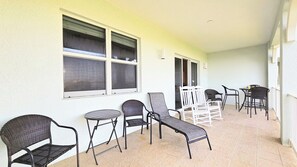 Un espace extérieur abrité, doté de nombreuses chaises et tables, de grandes fenêtres et d’un sol carrelé.