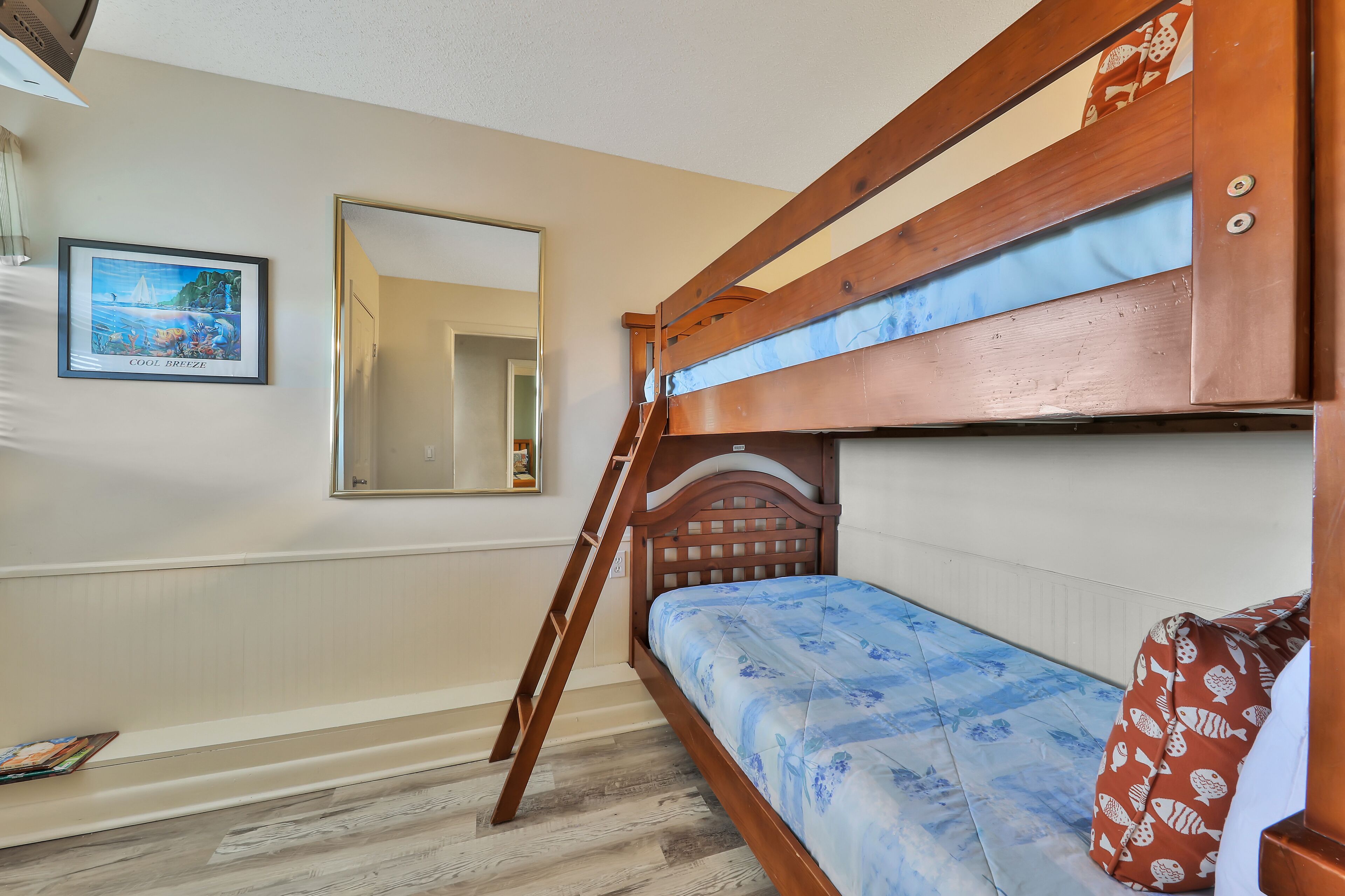 Una cama litera con escalera de madera, un cuadro en la pared y un espejo.