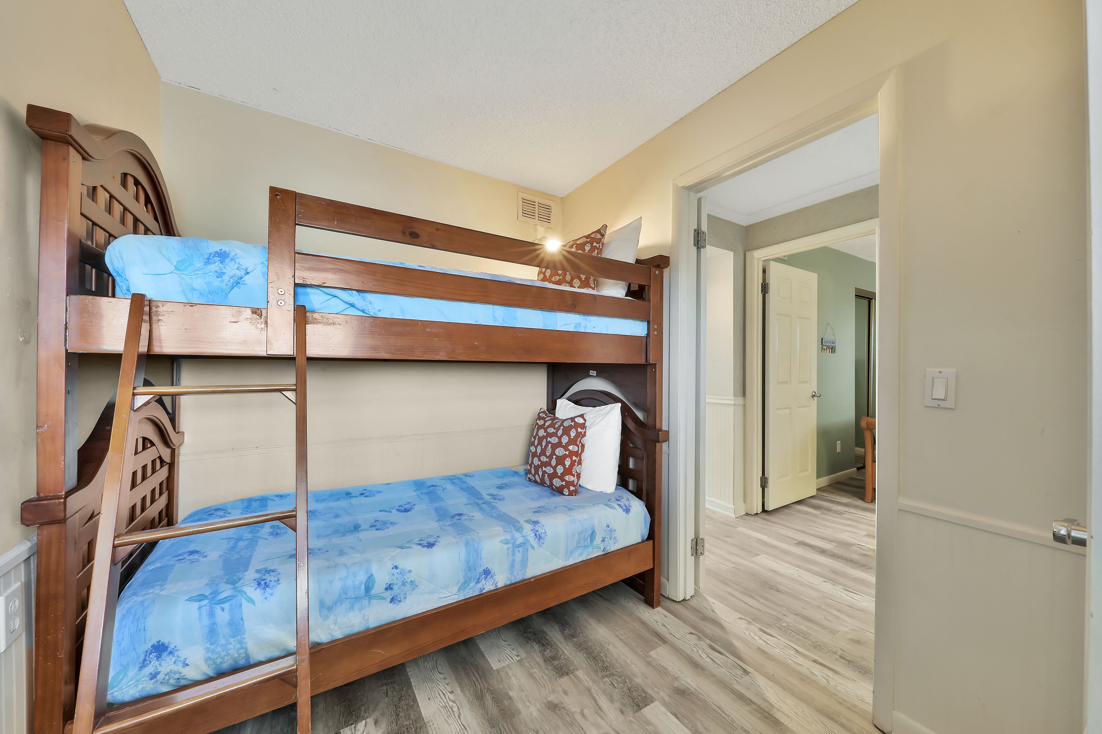 A bunk bed with a blue floral bedspread and a wooden headboard.
