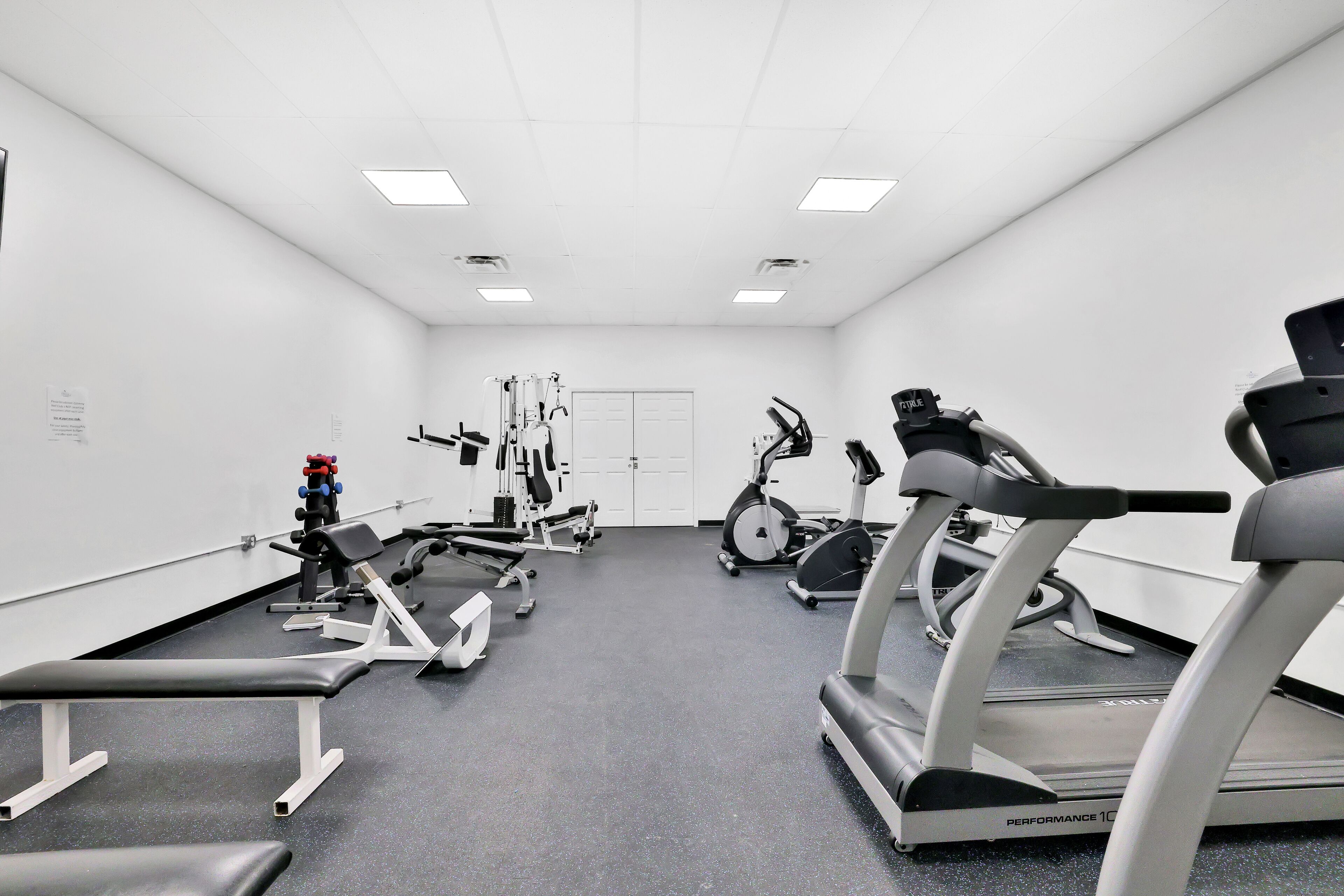 Et fitnesscenter med forskellig træningsudstyr, herunder løbebånd, spinningcykler og styrkemaskiner.