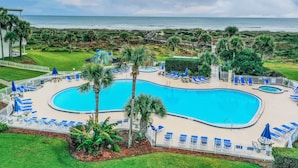 A pool area with a large pool, blue lounge chairs, and palm trees. - Beautiful Home Near the Beach With Views of the Atlantic off the Private Balcony (St. Augustine)