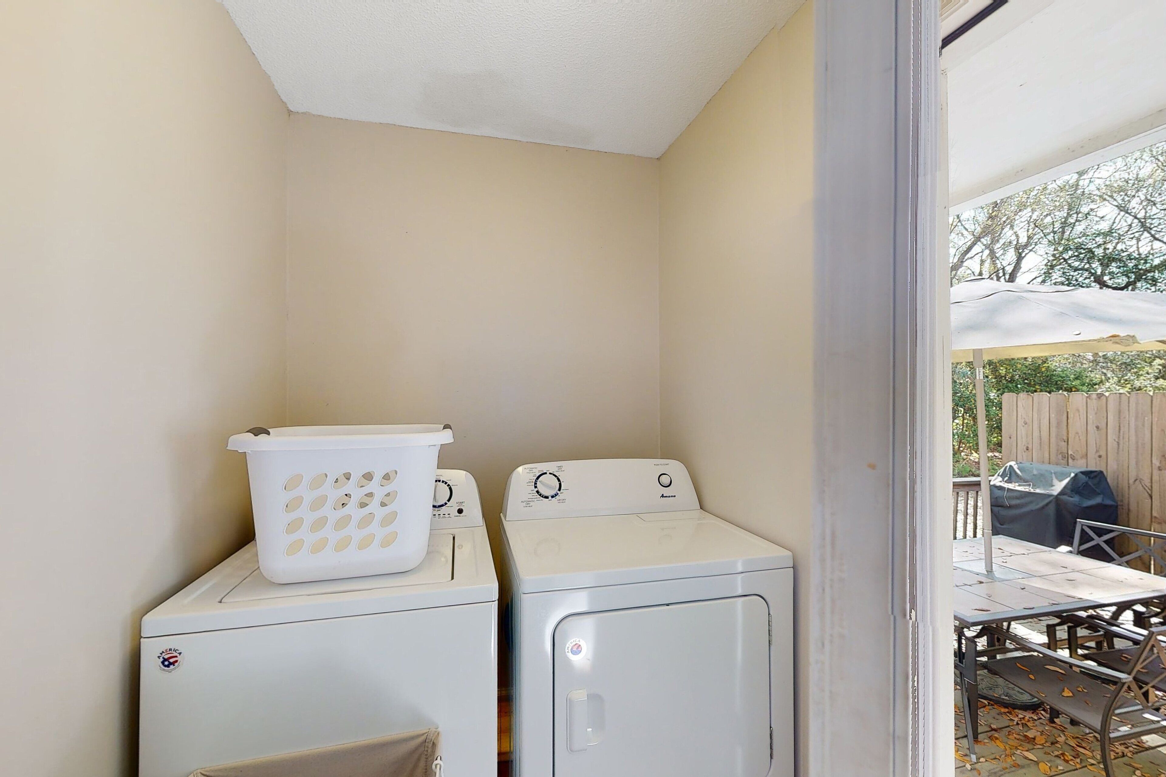 A laundry area with two white washing machines and a white laundry basket on top of the left machine.