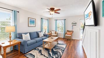 A living room with a blue sofa, wooden coffee table, and a ceiling fan.