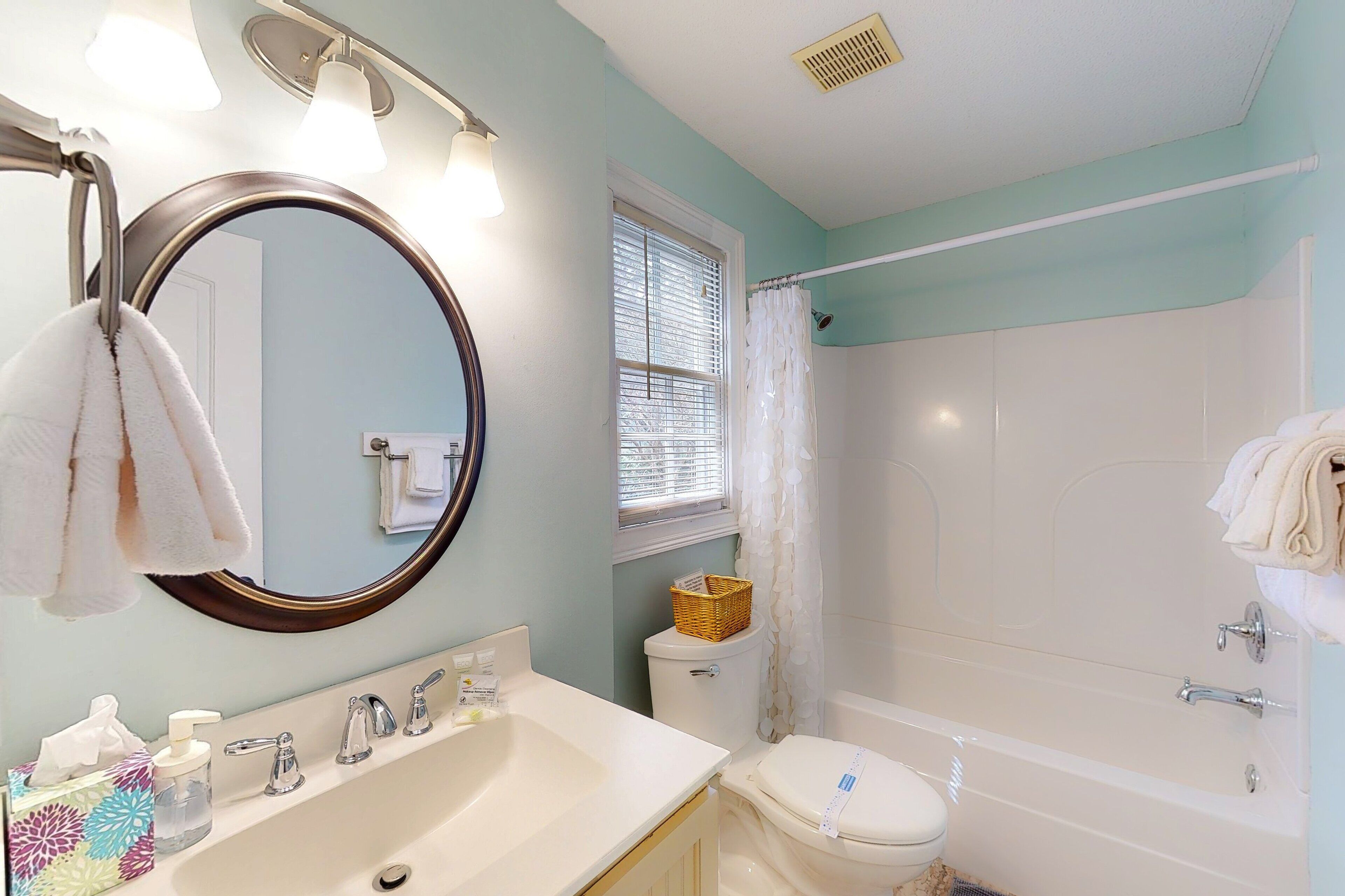 A bathroom with a sink, mirror, toilet, and bathtub.