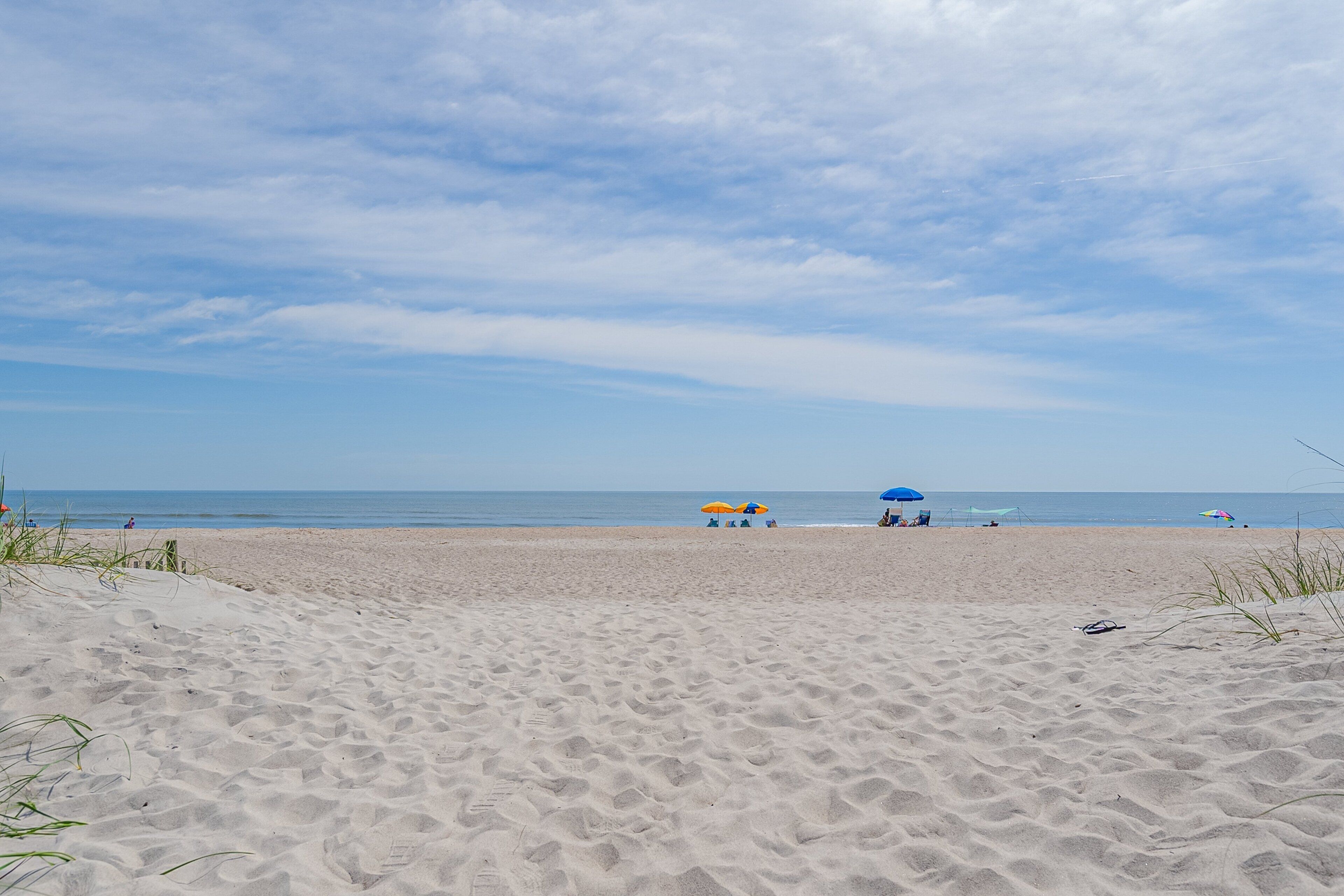 A sandy beach with umbrellas and people in the distance.