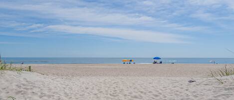 A sandy beach with umbrellas and people in the distance.