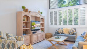 Un salon comprenant un téléviseur, deux canapés, une table basse et un meuble en bois.