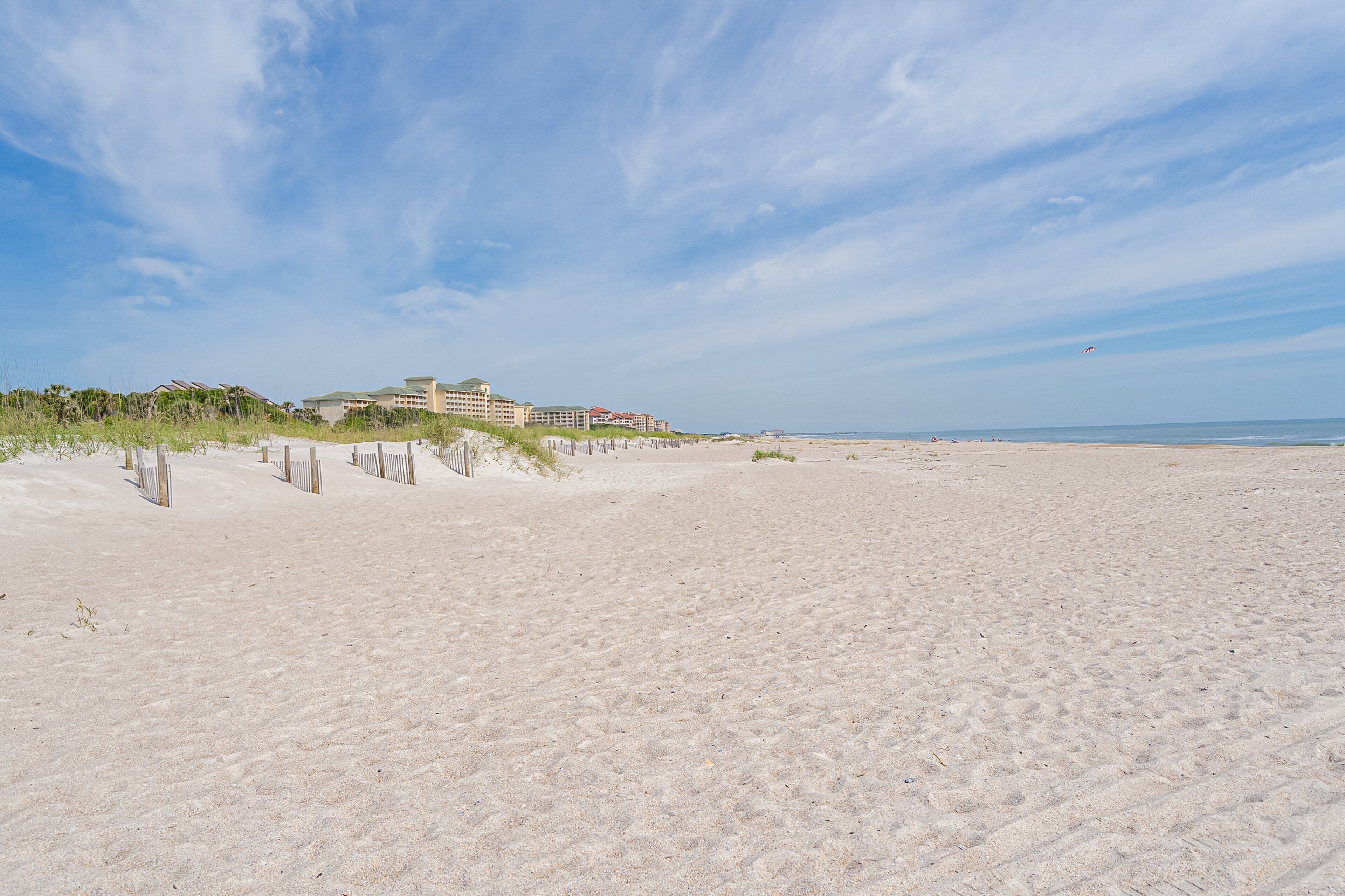 Una spiaggia con un albergo sullo sfondo.
