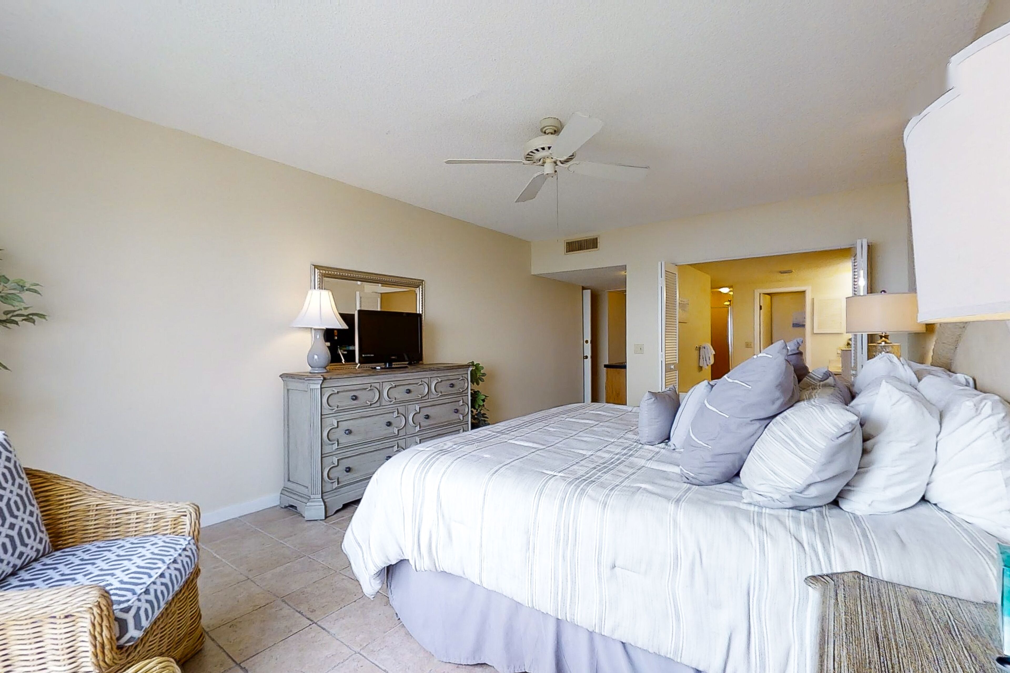 A bedroom with a bed, dresser, and two chairs.