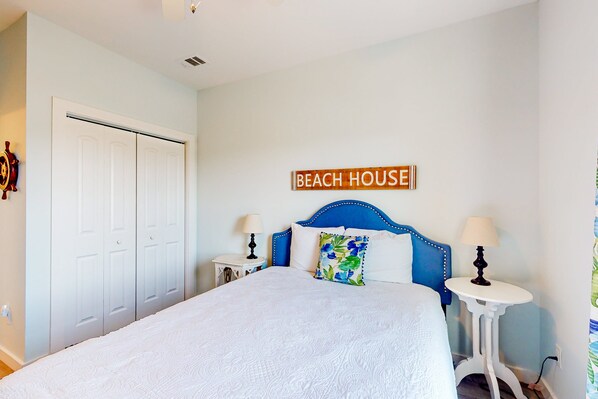 A bedroom with a bed, two bedside tables, a headboard, and a sign that reads "BEACH HOUSE". - Charming Home Steps From the Beach With Enclosed Yard and Grill - Dog-friendly (St. Augustine)