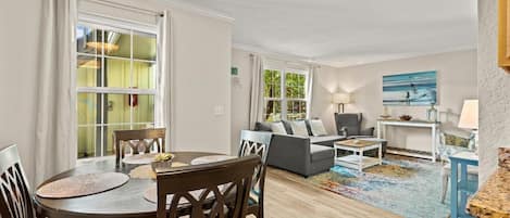 A spacious living room with a dining area, a sofa set, and a large window.