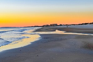A beach with a sunset, calm waters, and buildings in the background. - Cozy Cottage Near the Beach With Internet, AC, Washer/dryer (Fernandina Beach)