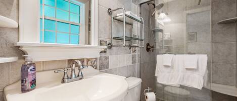 A bathroom with a white sink, a glass shower enclosure, and a toilet.