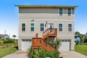 A two-story house with a front porch, a wooden staircase, and a garage. - Beautiful 3-level Home Steps From the Beach W/wifi, Washer/dryer, & Central AC (Fernandina Beach)