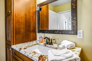 A bathroom with a wooden vanity, a marble sink, a mirror, and a bottle of soap. - Beautiful 3-level Home Steps From the Beach W/wifi, Washer/dryer, & Central AC (Fernandina Beach)