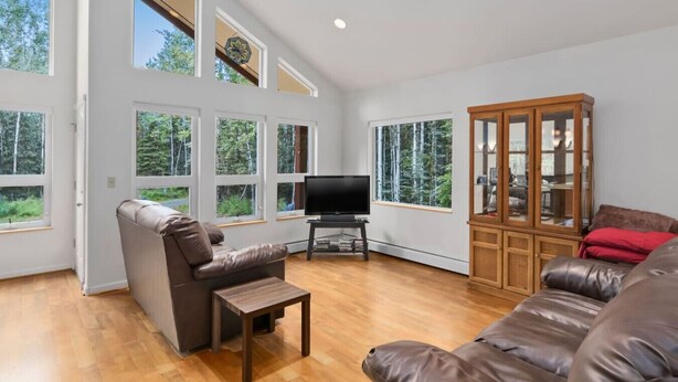 A spacious living room with a large window, a television, and a wooden cabinet.