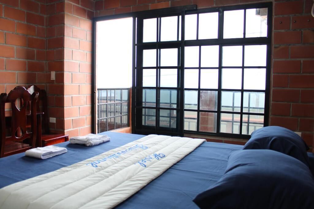 Une chambre avec un lit, une fenêtre donnant sur un beau paysage et une chaise.