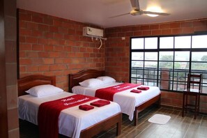 A room with two beds, a brick wall, a window, and a ceiling fan. - Hotel International (Pedernales)