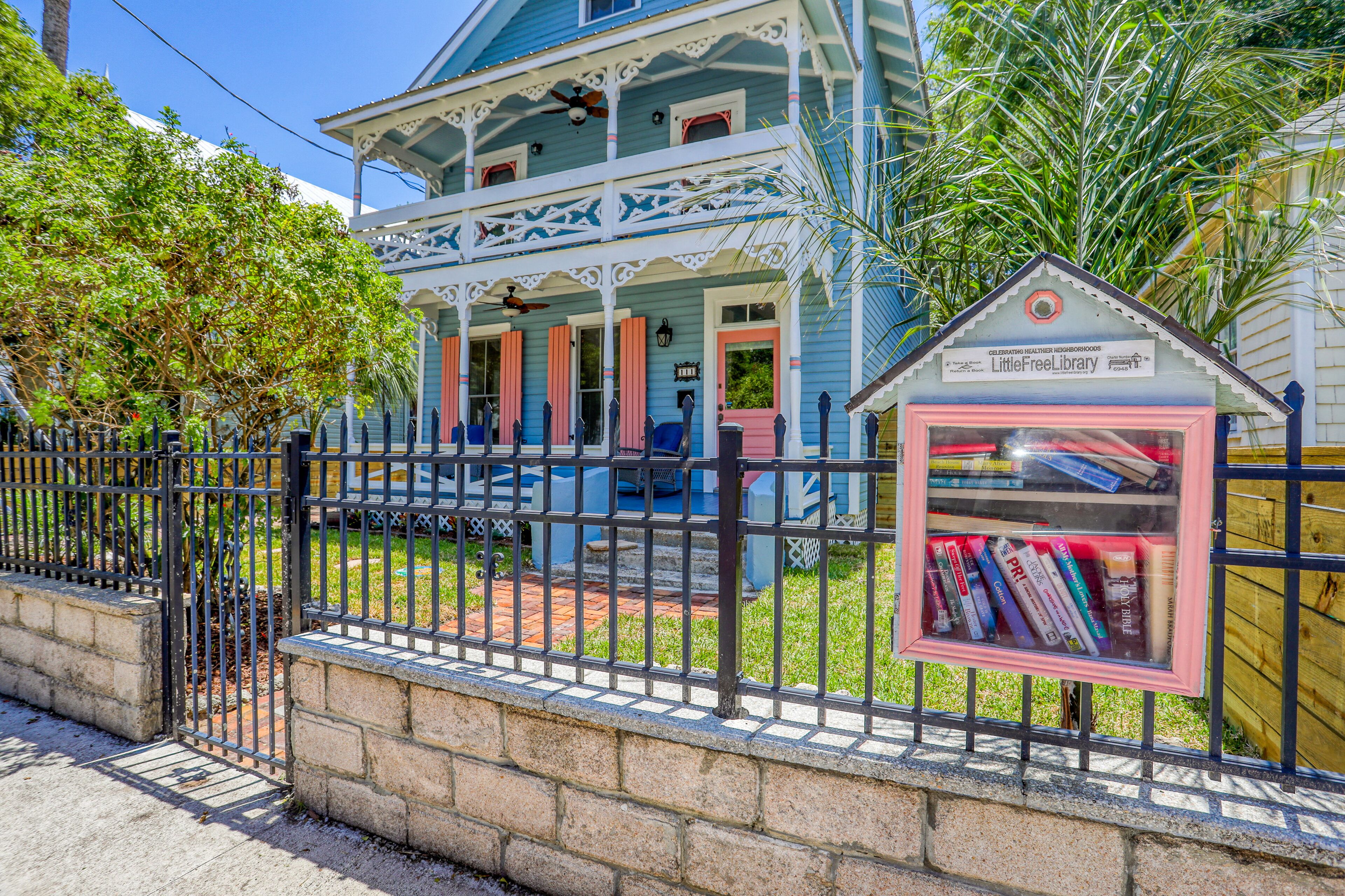 Una casa de dos pisos con un porche y un pequeño quiosco biblioteca.