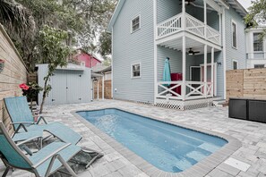 A backyard with a swimming pool, lounge chairs, and a house with a balcony. - Classic Victorian Home Near Downtown With a Private Pool, Wifi, & Washer/dryer (St. Augustine)