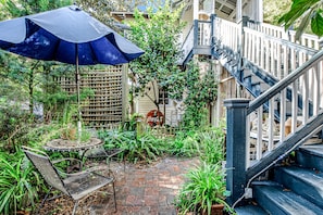 A patio with a table and chairs, a Coca-Cola sign, and a staircase. - Charming Getaway w/ a Kitchenette & Free Wifi - Walk to the Beach (St. Simons Island)