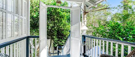 A covered porch with wicker furniture and a staircase leading to a garden.