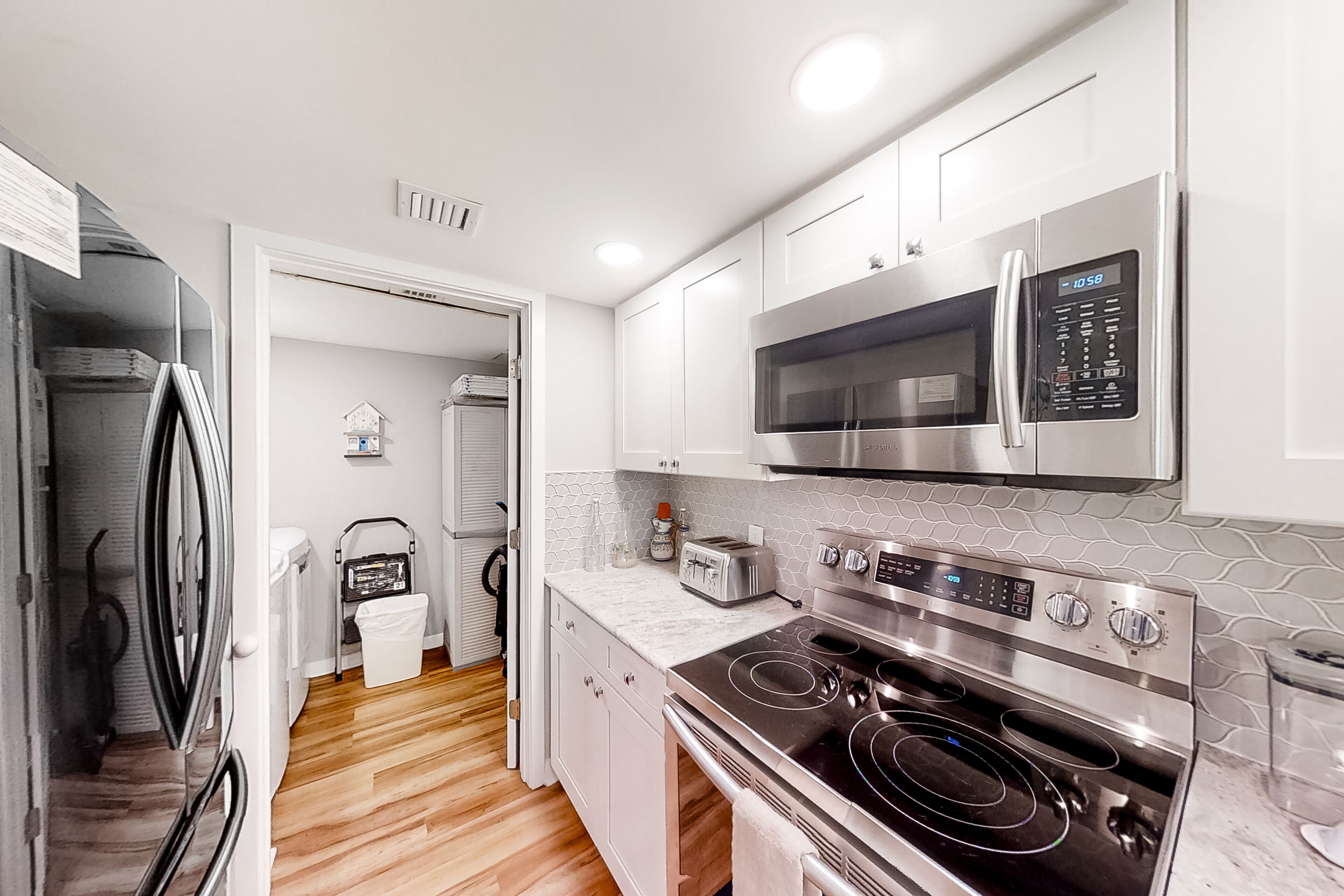 A modern kitchen with white cabinets, a stainless steel microwave, a built-in oven, and a gas stove.
