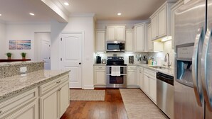 A modern kitchen with white cabinetry, stainless steel appliances, and a granite countertop. - Cozy Island Townhouse W/screened Porch, Shared Pool, & Serene Pond Views (St. Simons Island)
