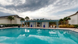A swimming pool with a covered area and lounge chairs. - Cozy Island Townhouse W/screened Porch, Shared Pool, & Serene Pond Views (St. Simons Island)