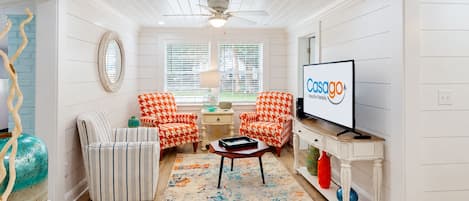 A modern living room with a television, two patterned armchairs, a coffee table, and a decorative rug.