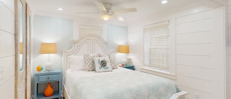 A bedroom with a bed, nightstands, a ceiling fan, and a window with blinds.