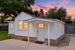A small, single-story house with a brick foundation, a front porch, and a chimney. - Cozy Cottage Near Beach/bars/dining With Enclosed Yard, AC, & W/D (St. Simons Island)