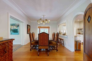 Un vaste espace dédié à la salle à manger, avec une longue table en bois et des chaises assorties, un lustre et une vue sur la cuisine.