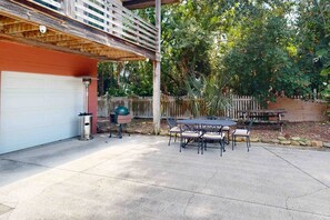 Une terrasse couverte avec une table et des chaises, un barbecue et un garage.