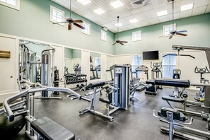 A gym with various exercise equipment, ceiling fans, and large windows. - Coastal Gem on the Golf Course w/ Shared Pool, & Beach Access - Dog-friendly (Palm Coast)